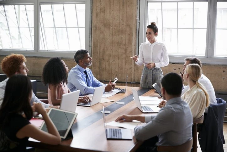 A leader presents ideas to colleagues around a working table.