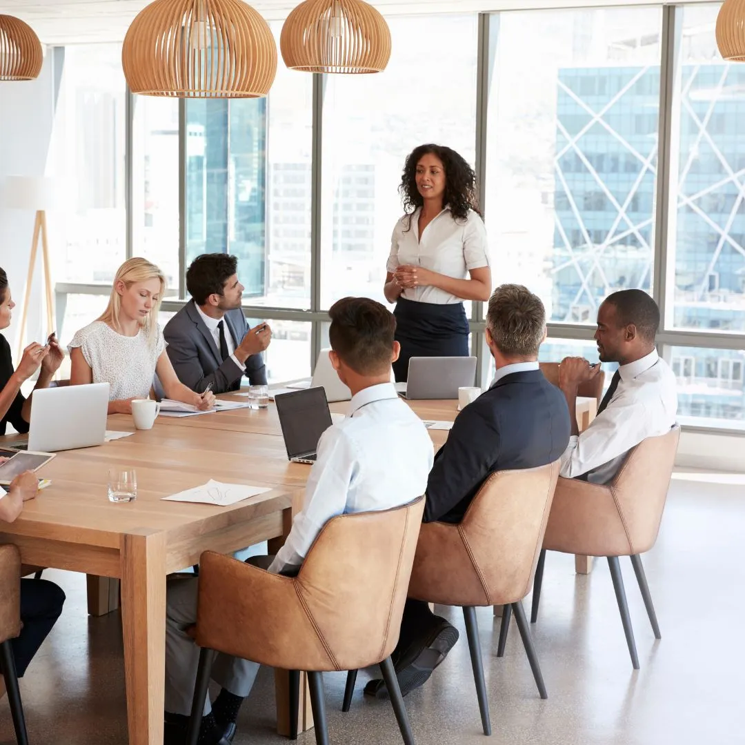 A presenter explains an idea to a diverse team gathered around a worktable.