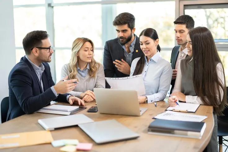 Institutional colleagues review plans together around a working table.