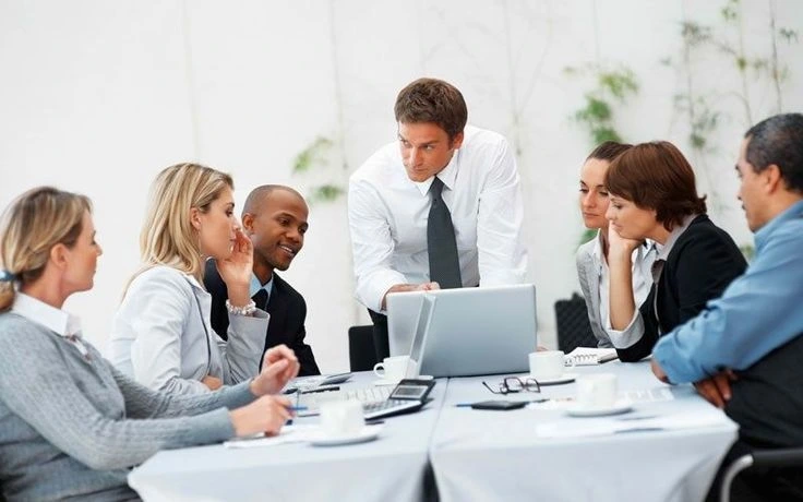 Professionals discuss a shared plan around a laptop.