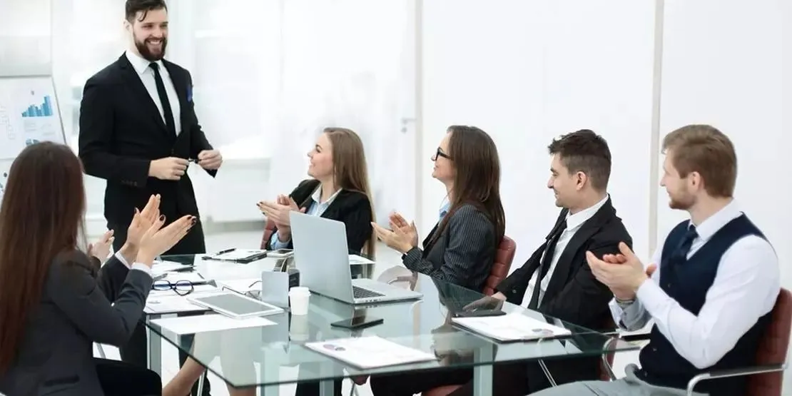 A presenter shares an idea with colleagues in a bright meeting space.