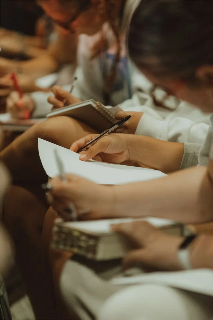A participant writes reflection notes during a learning session.