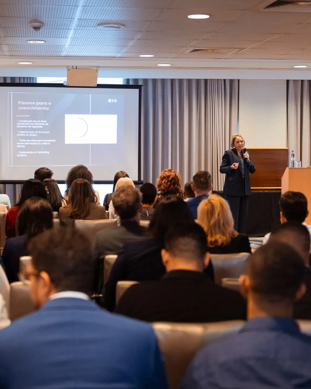 A speaker presents to a substantial audience at a large professional event.